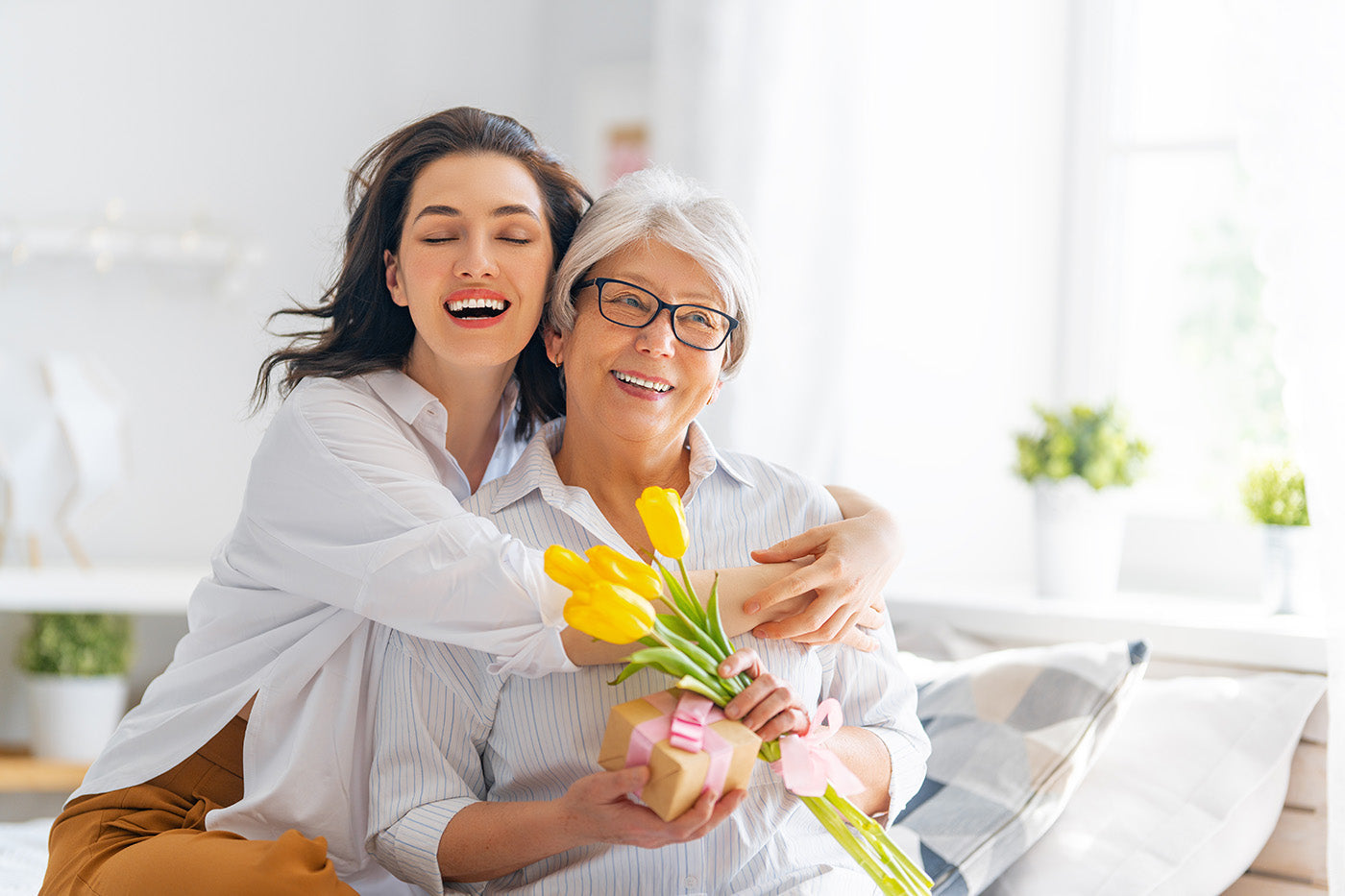 a daughter and her mother with a bunch of tulips, celebrating mothers day, hugging